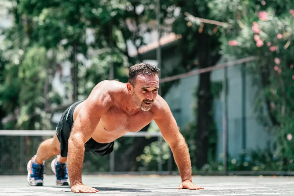 man doing pushups outdoors in sunny environment utc