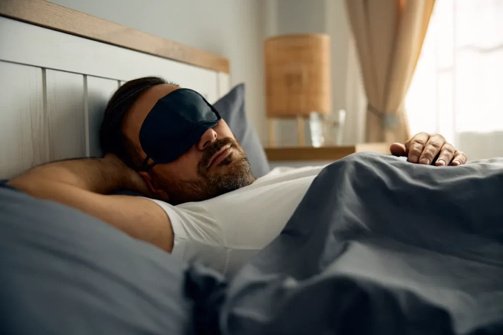 man sleeping peacefully in bed with eye mask utc