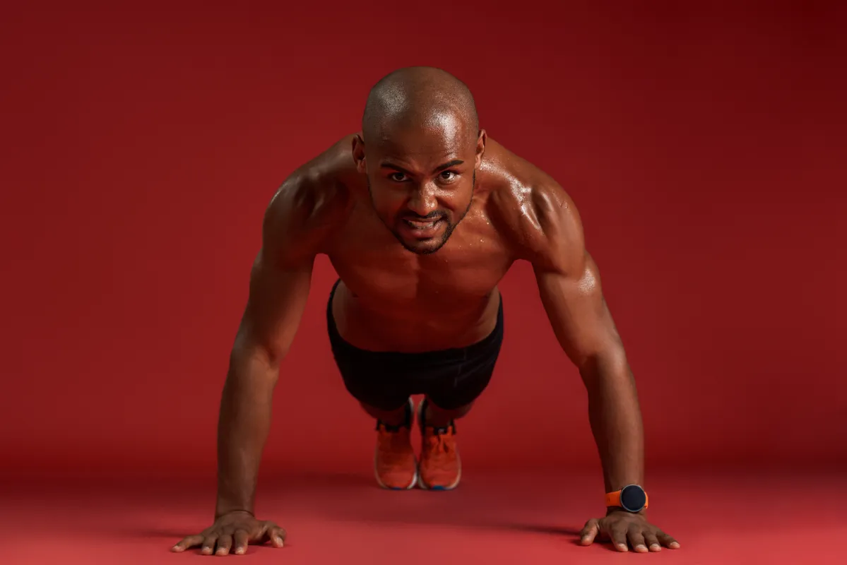 muscular man does push ups on red background utc