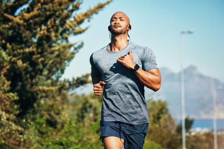 shot of a sporty young man running outdoors utc