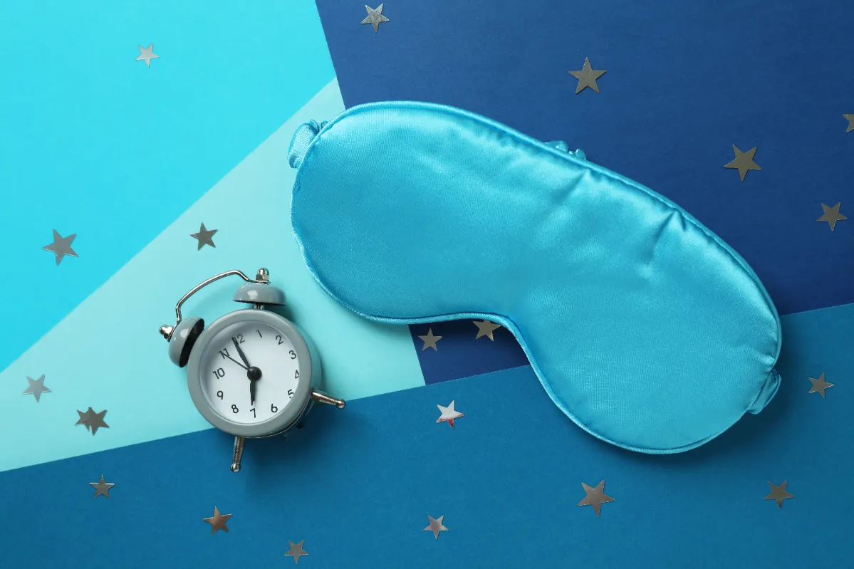 sleep mask and clock on blue background utc