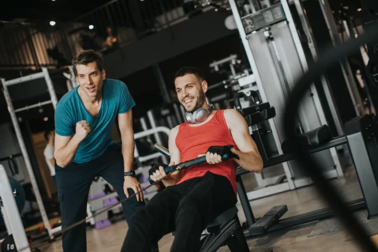 young man with trainer doing exercise in the gym utc