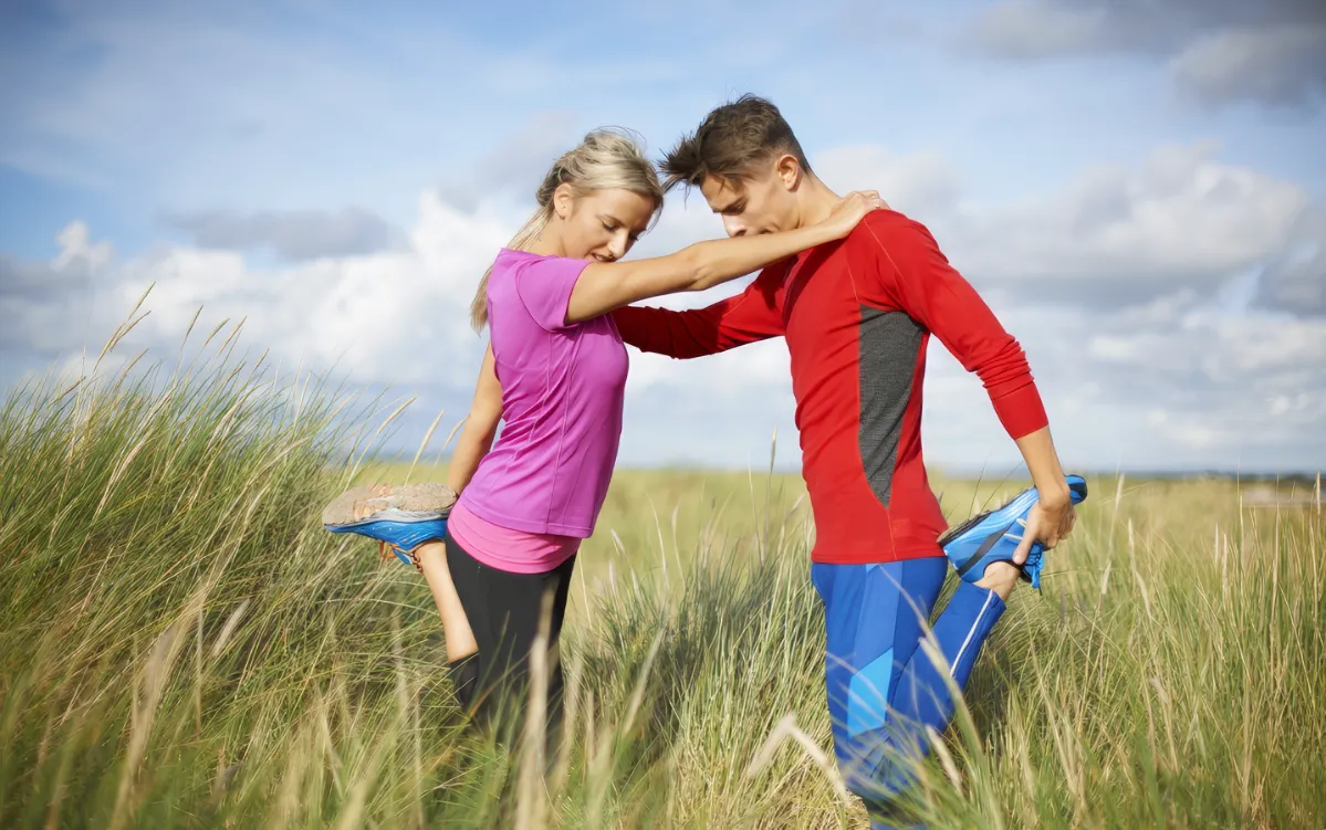 couple in tall grass on one leg doing stretching e utc