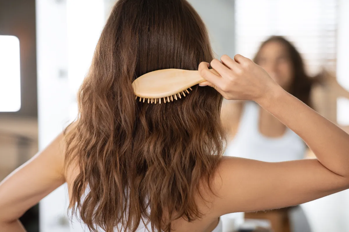 lady brushing hair with wooden hairbrush in bathro utc