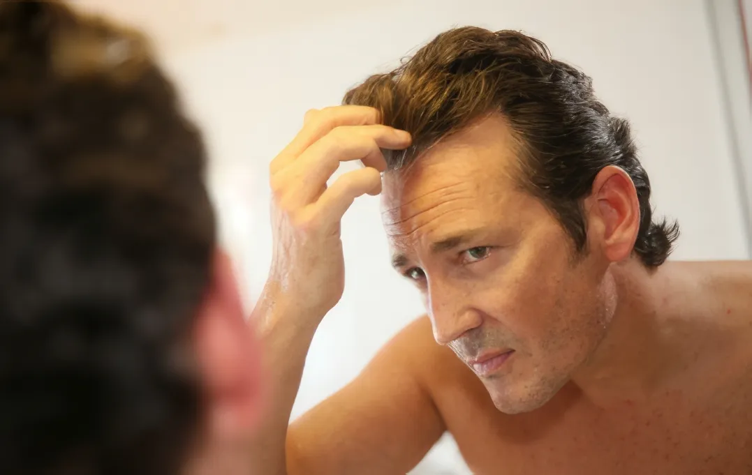 man inspecting his hair in a mirror utc