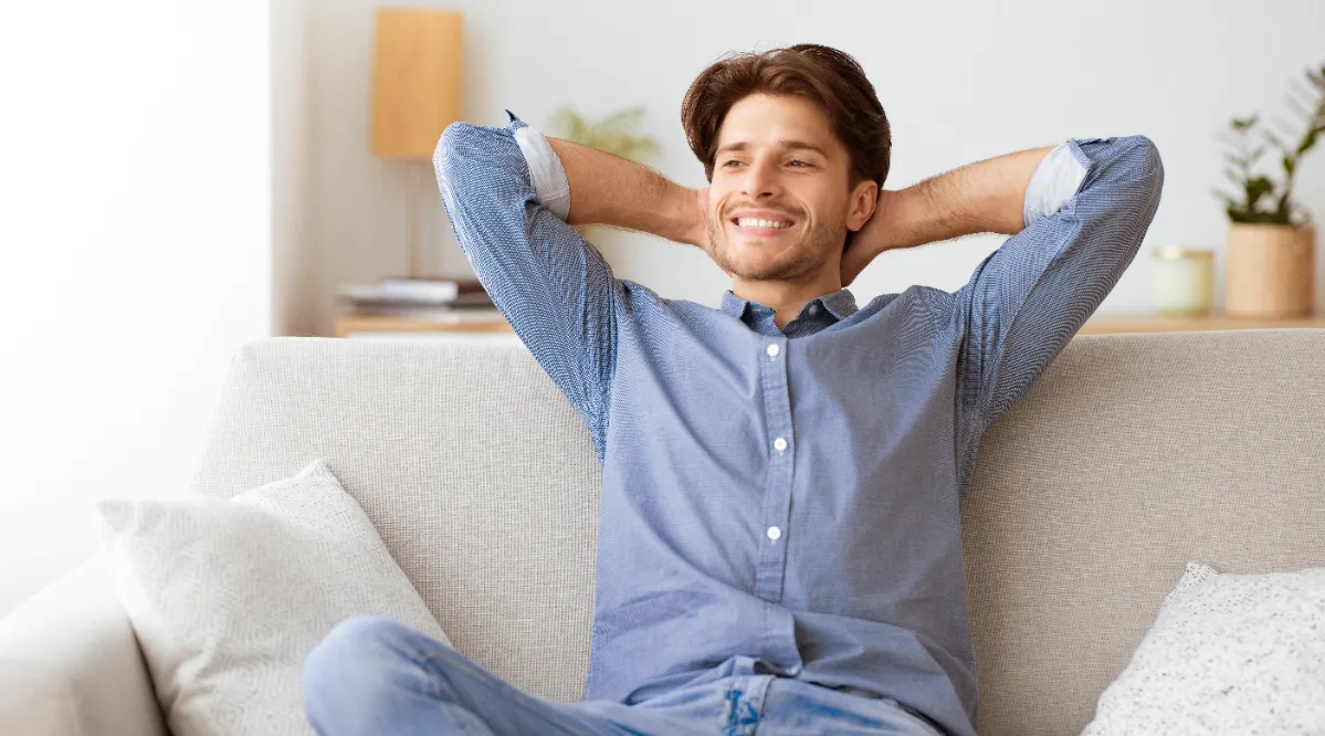 man relaxing on sofa with hands behind head utc