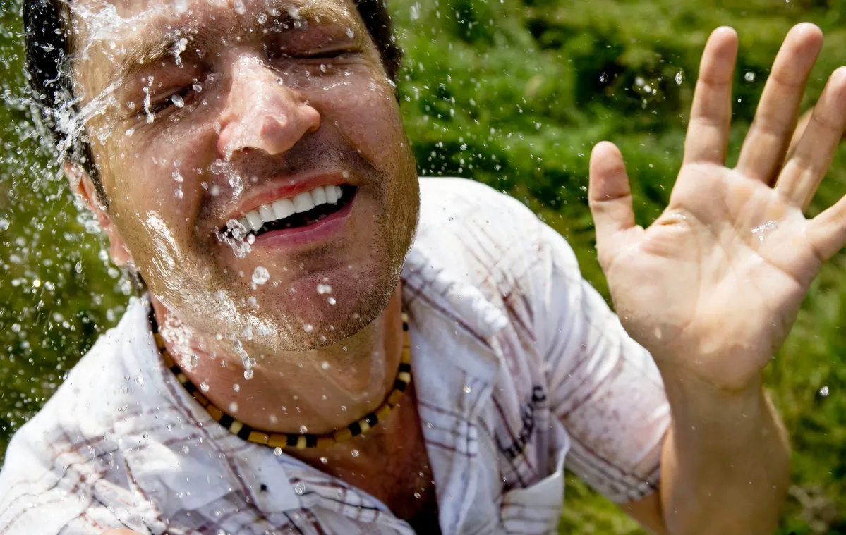 man splashing water on his face in nature utc