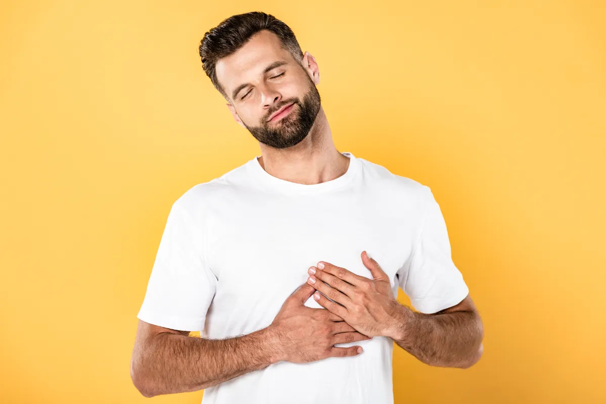 man with hands over chest on yellow background utc
