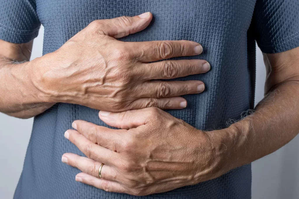 mature adult holding stomach in painful expression utc