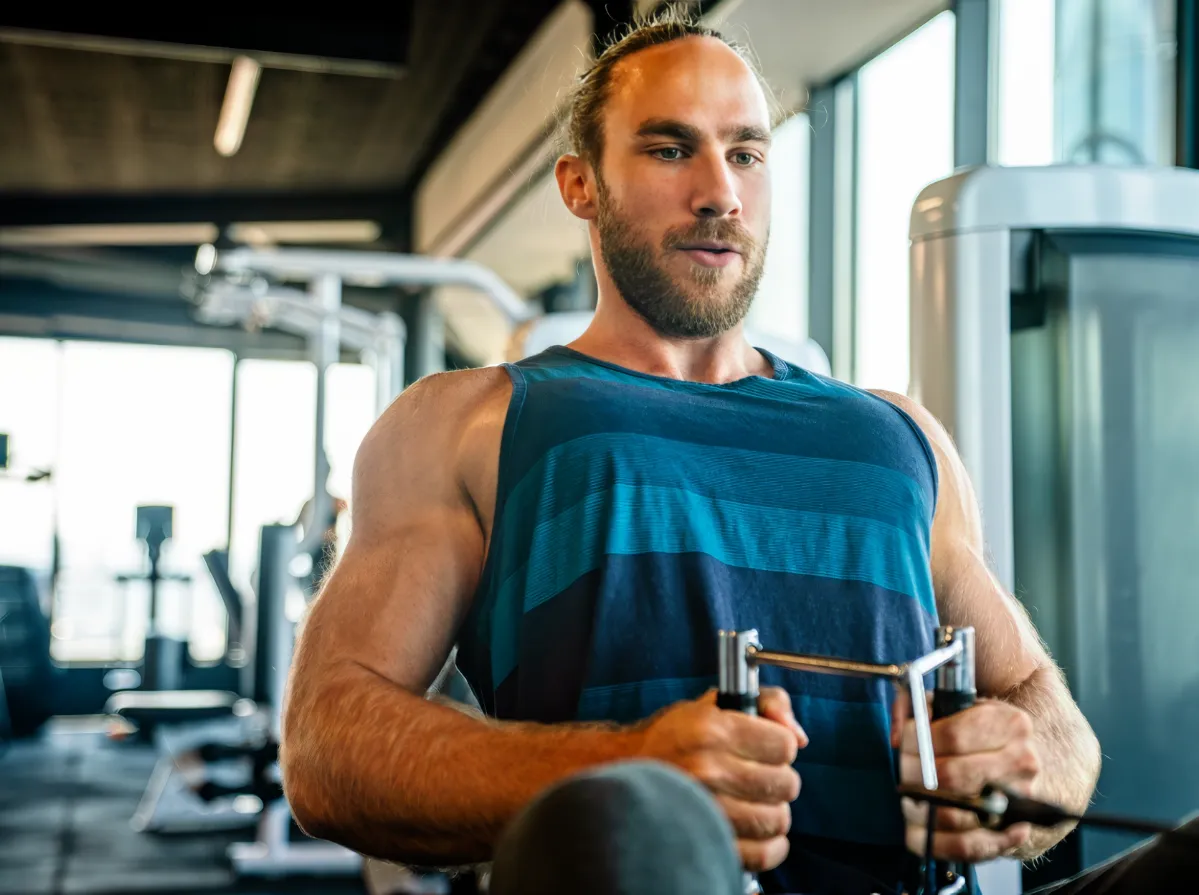 muscular man working out in gym doing exercises to utc