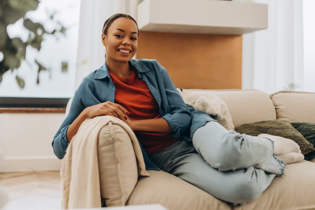 smiling woman relaxing on sofa in living room utc