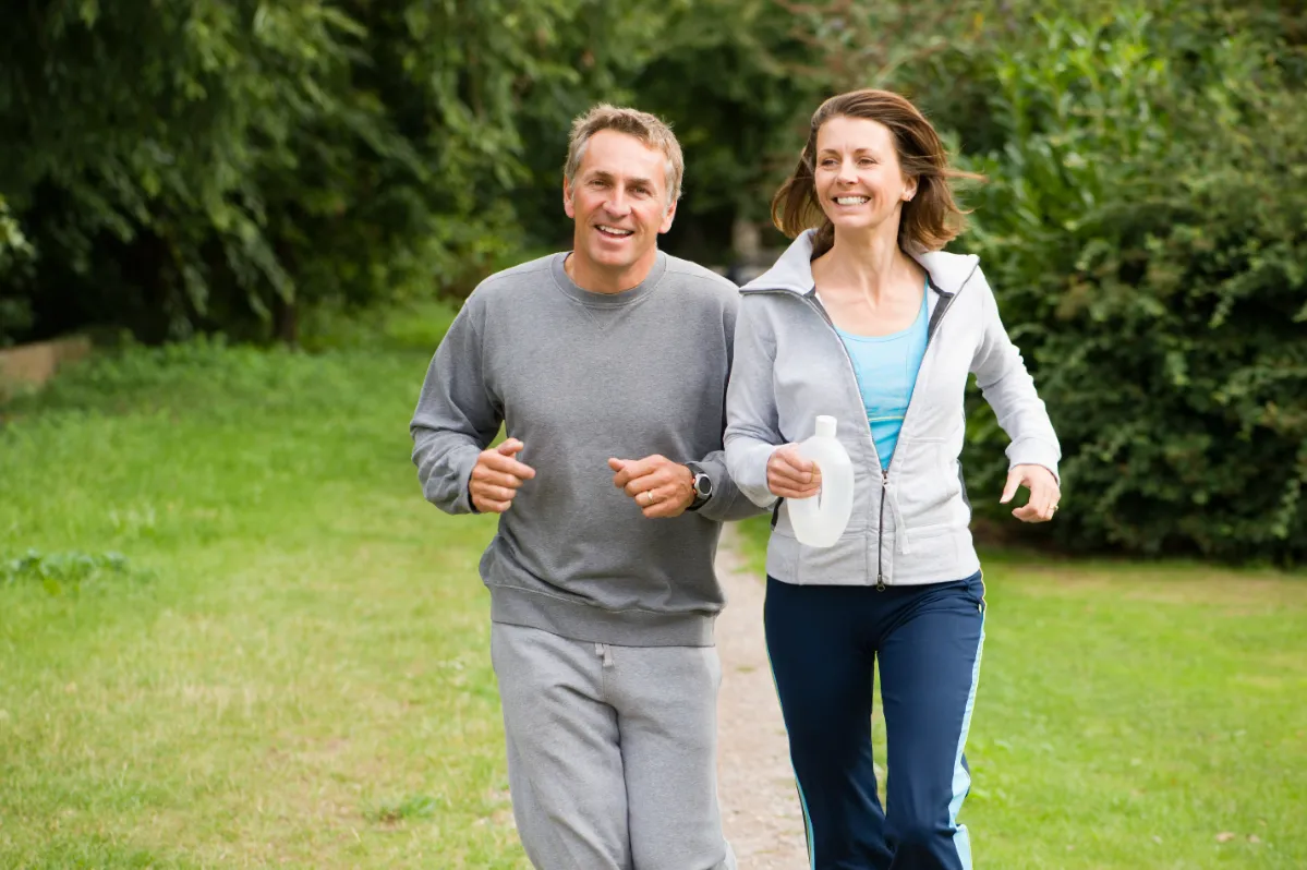 two people jogging in a lush green park utc