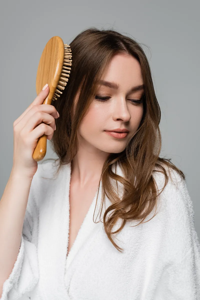young woman in bathrobe brushing shiny and healthy utc
